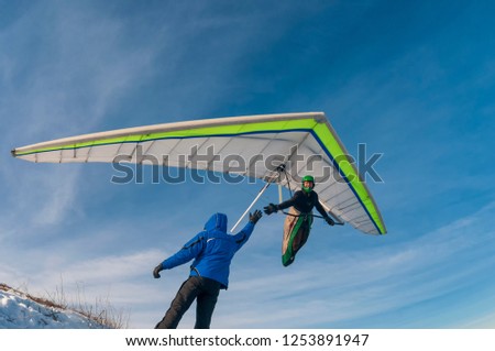 Man on the ground and hang glider pilot in the air shake hands. Inspiration to flying and lifetime achievement. 