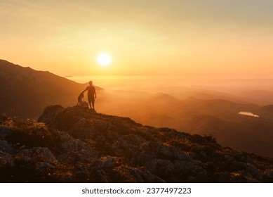 Man on his back with his dog contemplating the sunset in the mountains. Sport, adventure and hiking. traveling with a pet. - Powered by Shutterstock