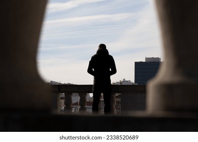 man on his back looking at the city in backlight, natural frame in backlight of young man looking at the city