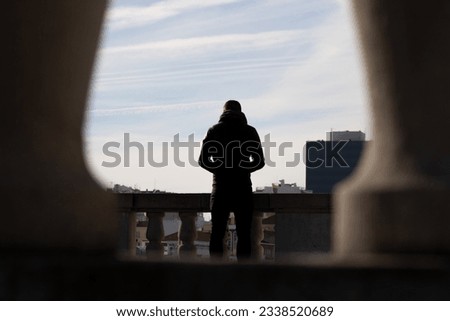 man on his back looking at the city in backlight, natural frame in backlight of young man looking at the city
