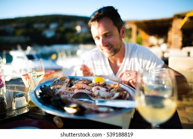 Man On Holiday, Sitting Outside At Sunset, Eating Seafood