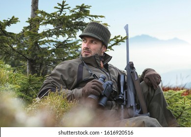 The man is on the hunt. Hunting period. Male with gun. Hunter with hunting gun and hunting form to hunt.   In the background spruce forests