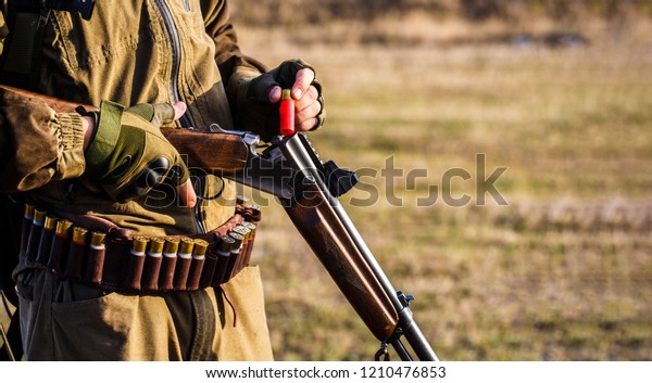 The man is on the hunt, sport. Hunter man.\
Hunting period. Male with a gun, rifle. Man is charging a hunting\
rifle. Process of hunting during hunting season. Male hunter in\
ready to hunt. Closeup.