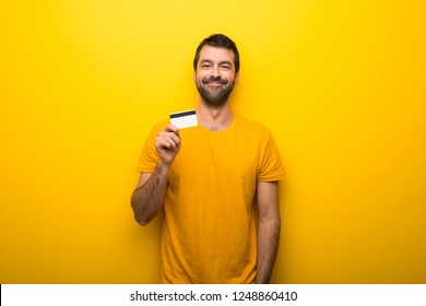 Man On Isolated Vibrant Yellow Color Holding A Credit Card