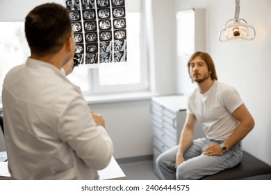 Man on medical appointment with urologist, doctor shows an X-ray of the patient's pelvis. Concept of men's health - Powered by Shutterstock