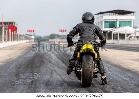 Man on motorbike on the road racing track riding, Biker sitting on motorcycle wearing helmet and leather jacket ready to race.