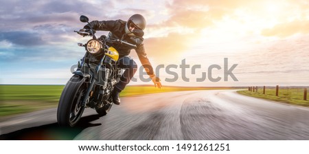 man on a motorbike on the road riding. having fun driving the empty road on a motorcycle tour journey. copyspace for your individual text.