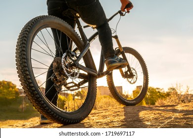 Man On Mountain Bike. Bicycle Wheels Close Up Image On Sunset. Low Angle View Of Cyclist Riding Mountain Bike. Foot On Pedal.