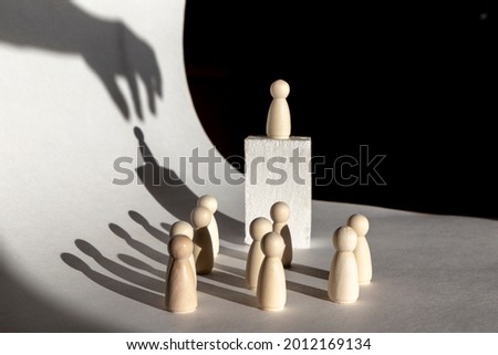 The man on the orator's pedestal is manipulated with a hand from above. Manipulation concept