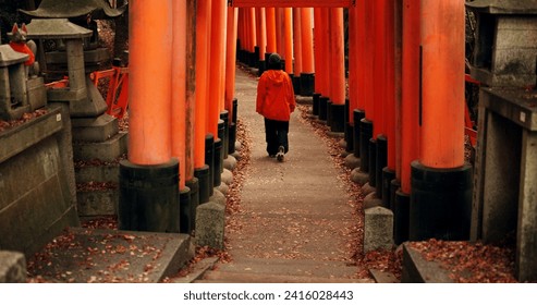 Man on path walking in Torii gate in Kyoto with peace, mindfulness and travel with spiritual history. Architecture, Japanese culture and person in orange tunnel at Shinto shrine in forest from back.
