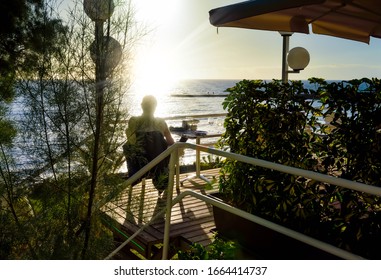 Man On A Patio Watching A Beautiful Sunset Over The Ocean