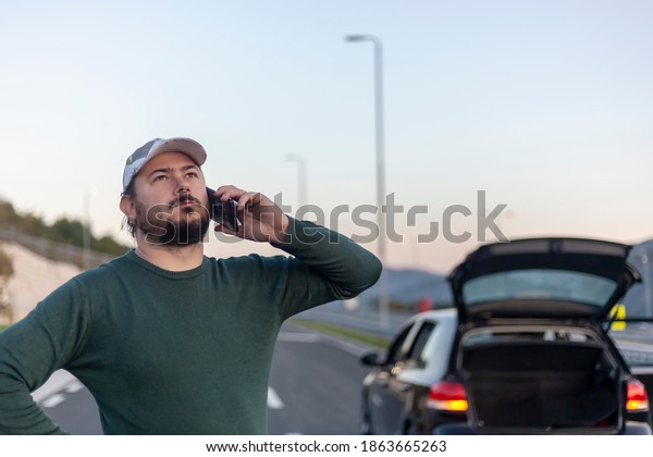 A man on the phone calls for help on the\
road. Problem with the car on the\
road.