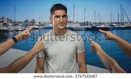 Man on a port dock with multiple hands pointing fingers at him, pointing gesture and bare forearms visible; shame judgment.