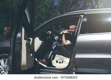 a man on a prosthetic leg sits in a car. Dressed in black jeans and a T-shirt - Powered by Shutterstock