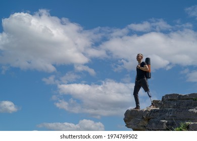 a man on a prosthetic leg travels the mountains. Dressed in black jeans and a T-shirt, he carrying mat - Powered by Shutterstock