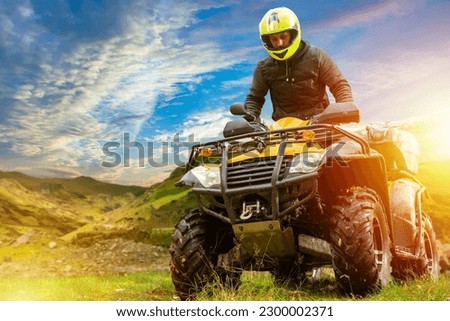 Man on quad bike. ATV driver. Extreme racing. Man in helmet drives ATV motorcycle. Off-road racing. Guy participates in extreme competitions. ATV under blue sky. Male with quad in scenic area