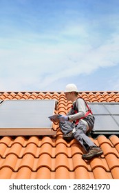 Man On Roof Top Checking On Solar Panel Installation