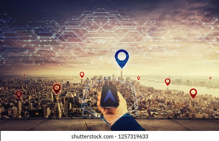 Man on the rooftop holding a mobile phone, blue gps arrow follow the correct way to pointer over big city horizon. Searching location navigation route. Modern technology concept virtual reality maps.