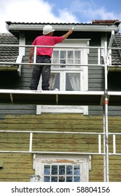 Man On A Scaffold Painting An Old House