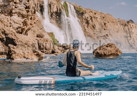 man on a SUP board near huge Duden waterfall in Antalya, Turkey. Summer watersports and recreation and adventure concept