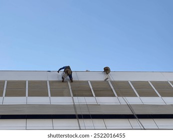 Man on top of a building, working on cleaning windows.