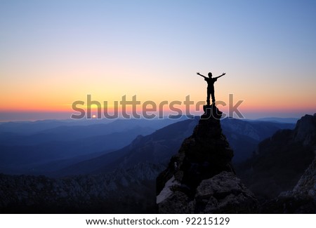 man on top of the mountain looking to the sun