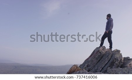 Man on top of the mountain. A young, athletic man stands on a high rock