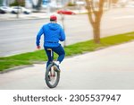 Man on unicycle moving fast along sidewalk, motion blur. Elderly person ride on one wheel bike. Man riding monocycle at city street, active lifestyle
