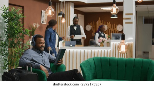 Man on videocall conference in hotel lobby, calling family and friends to discuss about travelling on holiday while he waits for room registration. Tourist using tablet for videoconference chat. - Powered by Shutterstock