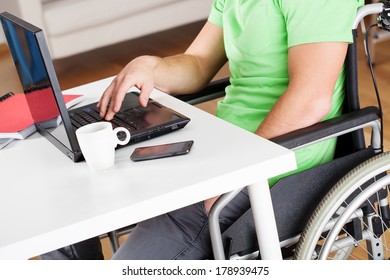 A Man On A Wheelchair Doing Some Office Work On His Latop