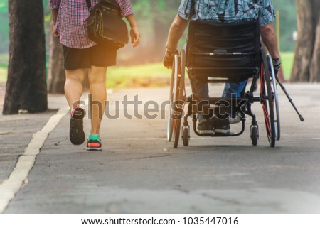 A man on wheelchair and his wife enjoying in the park,copy space.