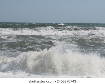 A man on a windsurfing board swims among rough waves on a sunny summer day - Powered by Shutterstock