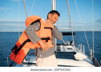 Man on a yacht putting on a life jacket