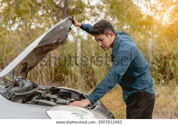 Man open car hood for repair as maintenance\
service. Man trying to check a car engine, looking inside open\
bonnet. Car broken concept.
