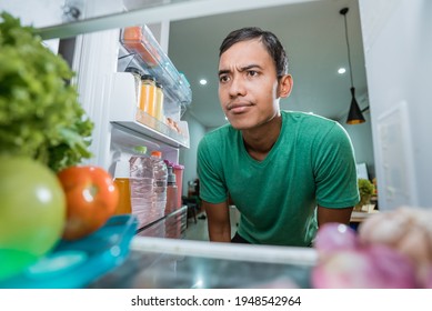 man open fridge door and confuse looking something to eat - Powered by Shutterstock