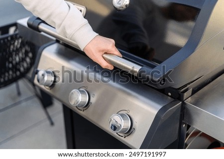Man open lid and checking fire in bbq grill, looking if burned down to hot coals ready for cooking meat. Barbeque equipment, outdoors kitchen concepts