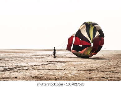 Man With Open Parachute After Landing In A Famous At Candolim Goa Near Baga Beach And Vagator Beach. Yellow And Blue Wings Slings Are Visible. Paragliding Parachuting Is Extreme Sport Of Recreation