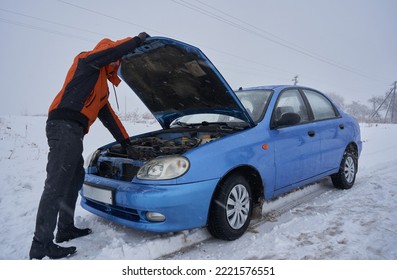 A Man Opened The Hood Of A Car In Winter,car Broke Down In The Winter, Man Inspecting The Car Engin