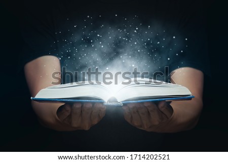 Man opened a magic book with growing lights and magic powder. Learning and education concept.
