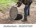 A man opened the septic tank hatch to check the sewer drain level. Septic tanks in a country house.