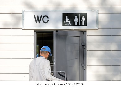 Man Opening Door To Public Toilet Front Close Up View Of Restroom Entrance With Wc Sign For Men Women Accessible Disabled Person In Street Bathroom Authentic Lifestyle Concept Natural Color Photo