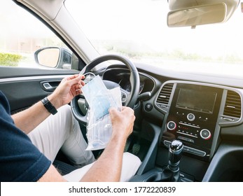 Man Opening An Envelope With Face Masks In The Car