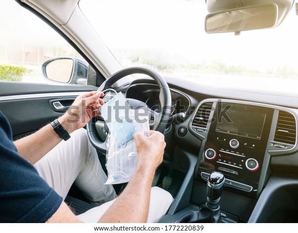 Man\
opening an envelope with face masks in the\
car