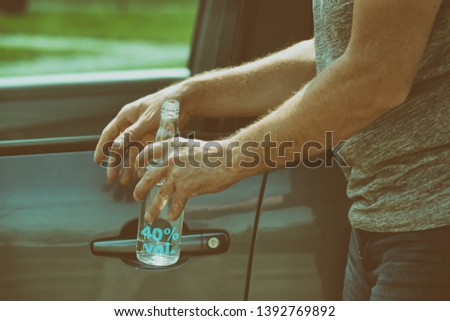 Man opening his car and holding a bottle of alcohol in hand. Don't drink and drive concept