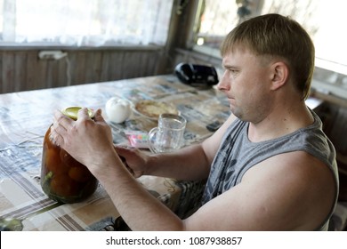 Man Opening Jar With Pickled Tomatoes At Home