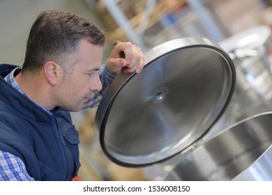 Man Opening A Large Metal Container In A Factory