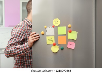 Man opening refrigerator door with paper sheets and magnets at home, closeup - Powered by Shutterstock