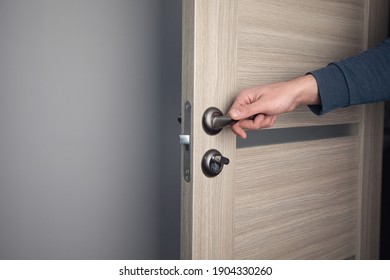 man opening wooden door in room