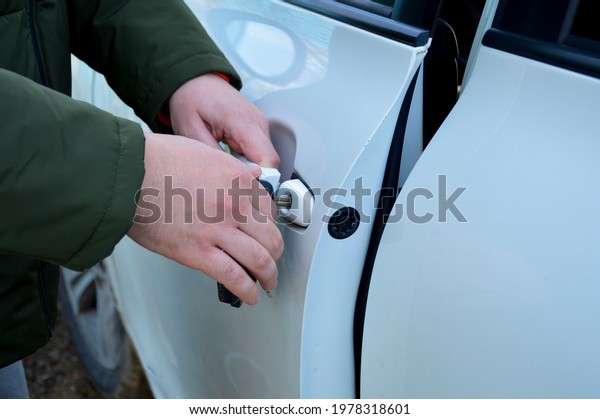 a man opens the car door with a\
key. one hand holds the key, the other pulls the\
handle