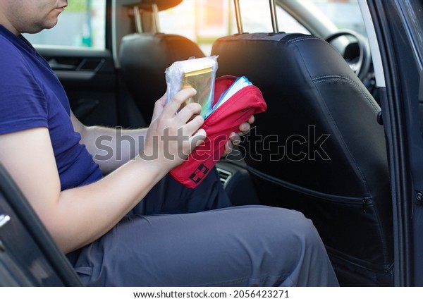 a\
man opens a car first aid kit in the car. The concept of first aid\
to the injured person in a road traffic accident. Availability of a\
first-aid kit when going through a technical\
inspection